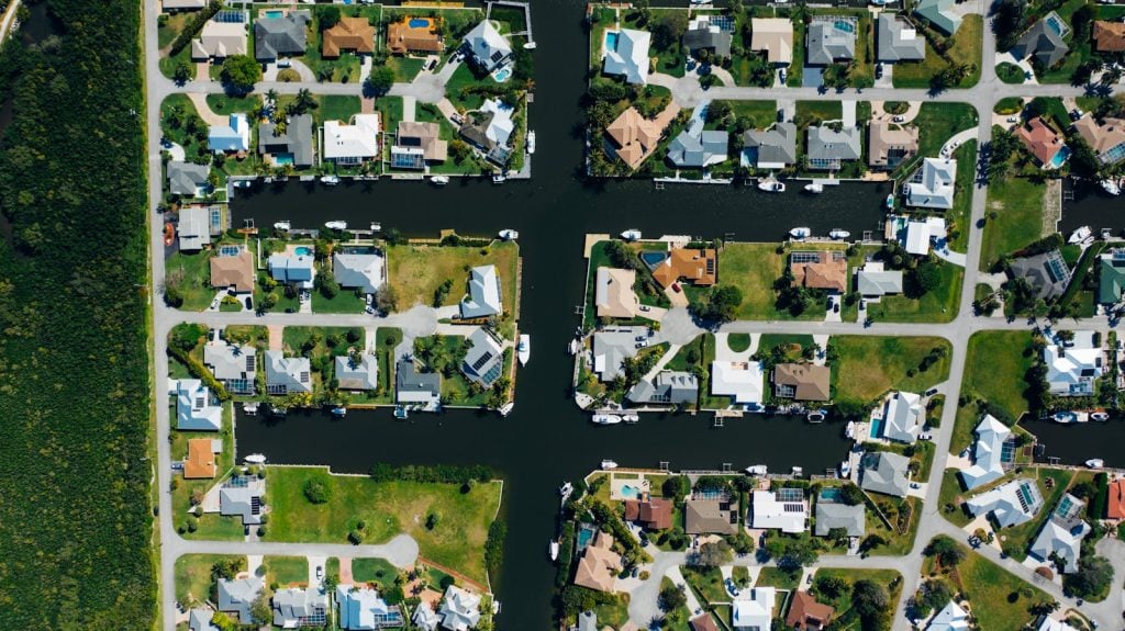 Drone shot of suburban canal-side homes arranged neatly with clear water channels.