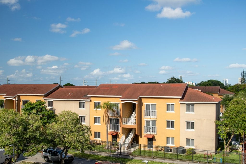 An apartment complex with cars parked in front of it