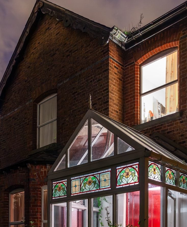 Brick house with stained glass sunroom at night