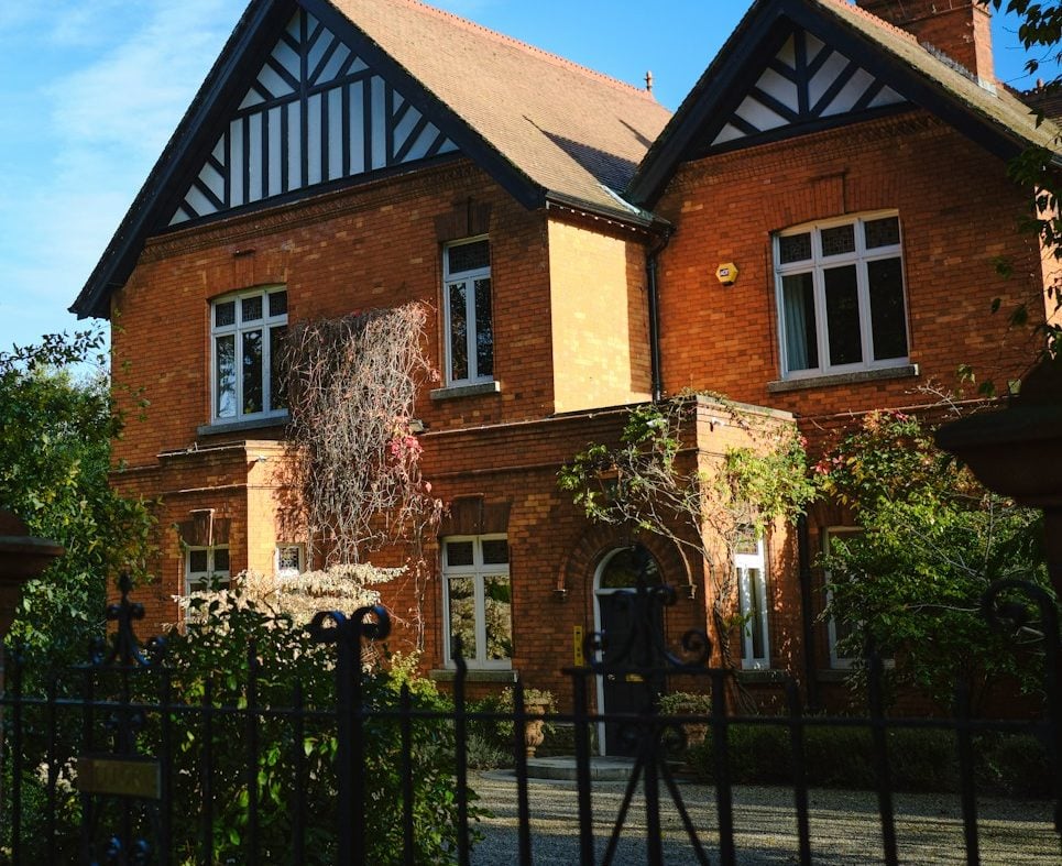 a large red brick house with a black iron fence