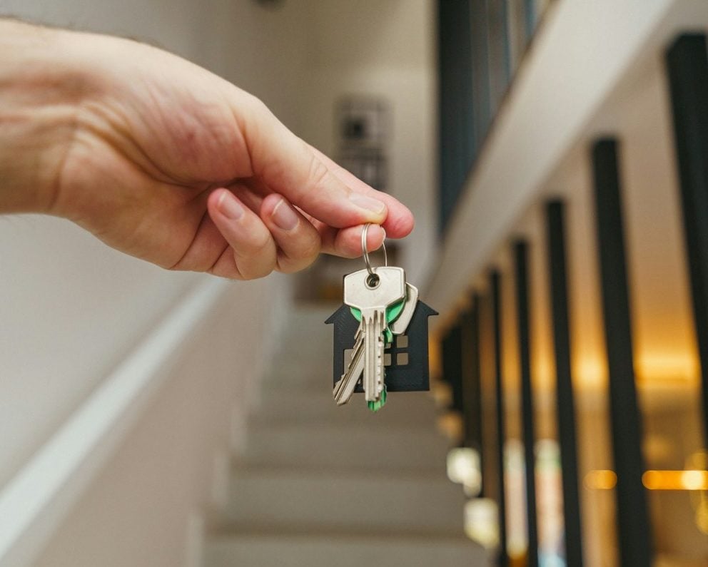 Here's a possible caption: keys being held in front of a staircase.