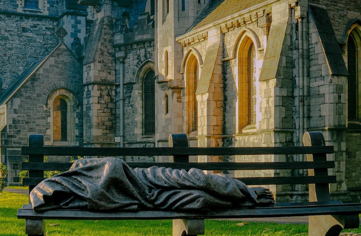 a statue of a person laying on a bench in front of a building