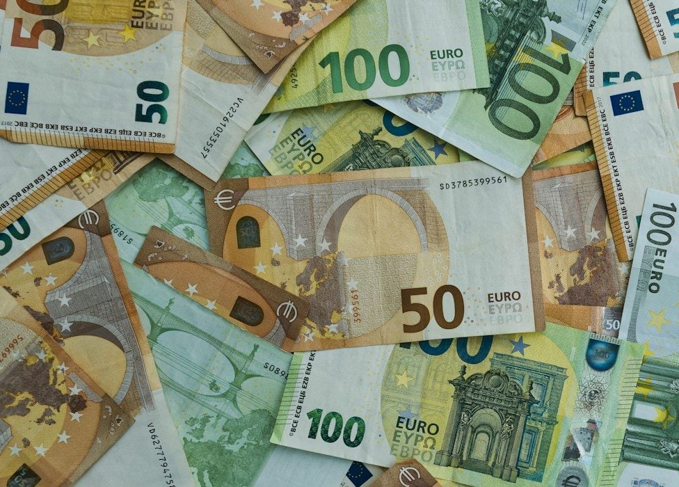 Scattered euro banknotes of 50 and 100 denominations.