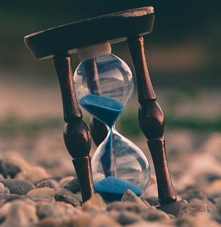 selective focus photo of brown and blue hourglass on stones
