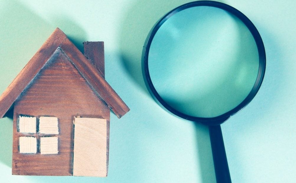 Magnifying glass over a wooden house model.