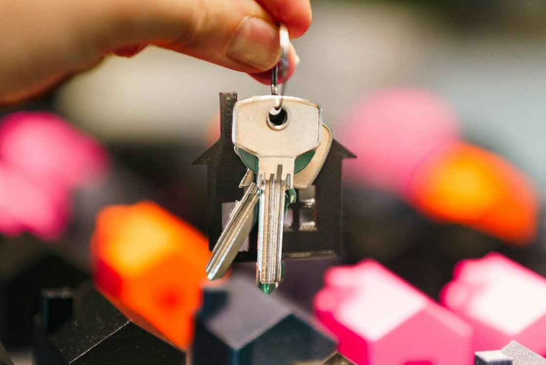 Hand holding house keys over miniature houses