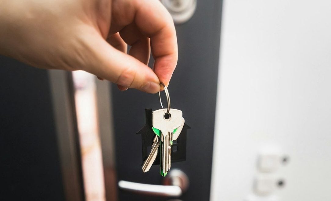A person is holding a key to a door